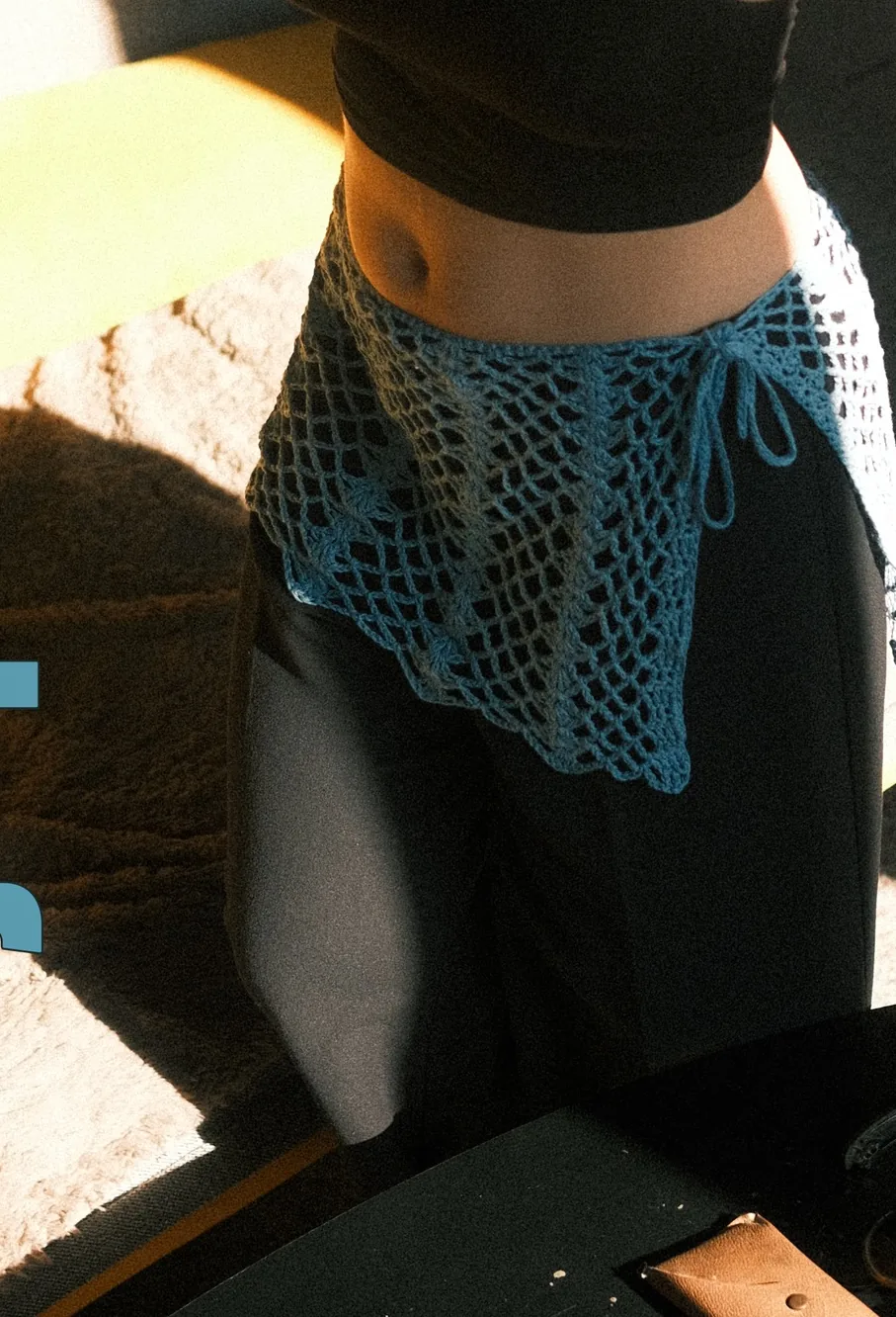 Surjupette bleue en crochet, portée sur un pantalon noir